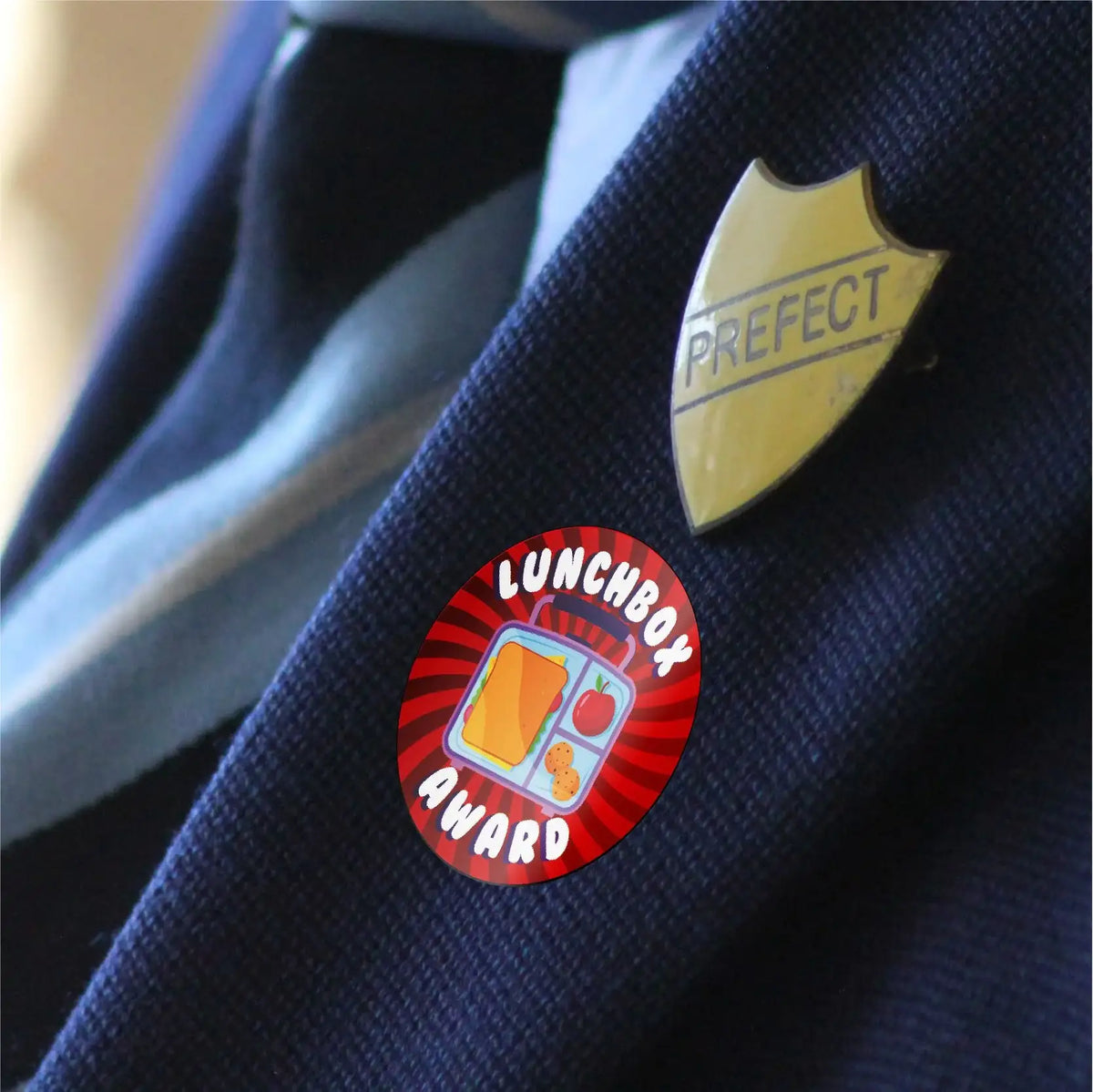 Lunchbox Award reward sticker and prefect badge on a student blazer
