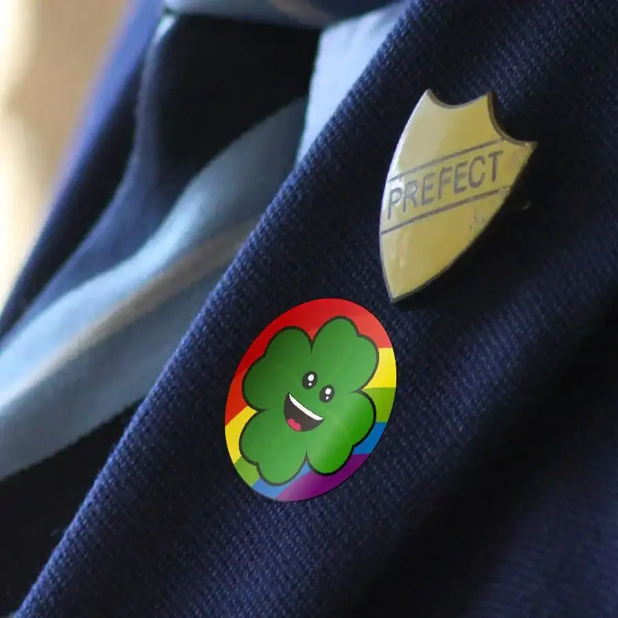 Smiling four-leaf clover reward sticker with rainbow border on school blazer lapel
