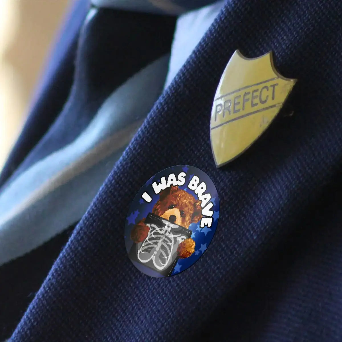 I Was Brave reward sticker with teddy bear and x-ray on a school uniform next to prefect badge