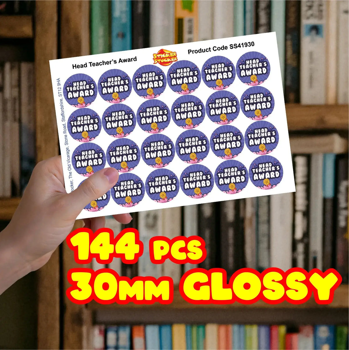 Sheet of glossy 30mm Head Teacher's Award reward stickers held in hand, bookshelves background