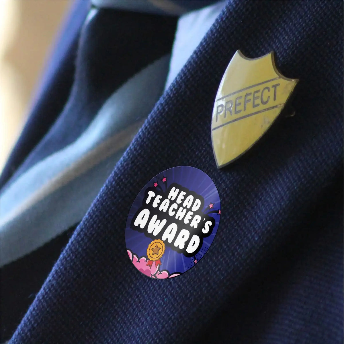 Head Teacher's Award reward sticker and prefect badge on a school uniform jacket.