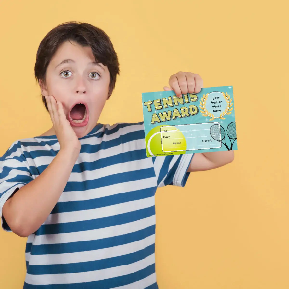 Surprised child in striped shirt holding tennis award certificate against yellow background