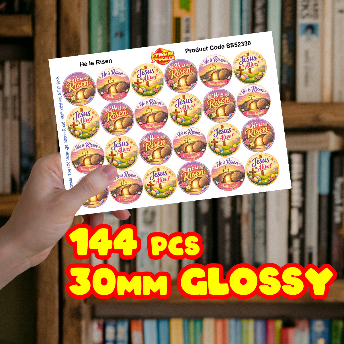 Hand holding a sheet of 30mm glossy Christian Easter reward stickers, 144 pieces, in front of bookshelves.