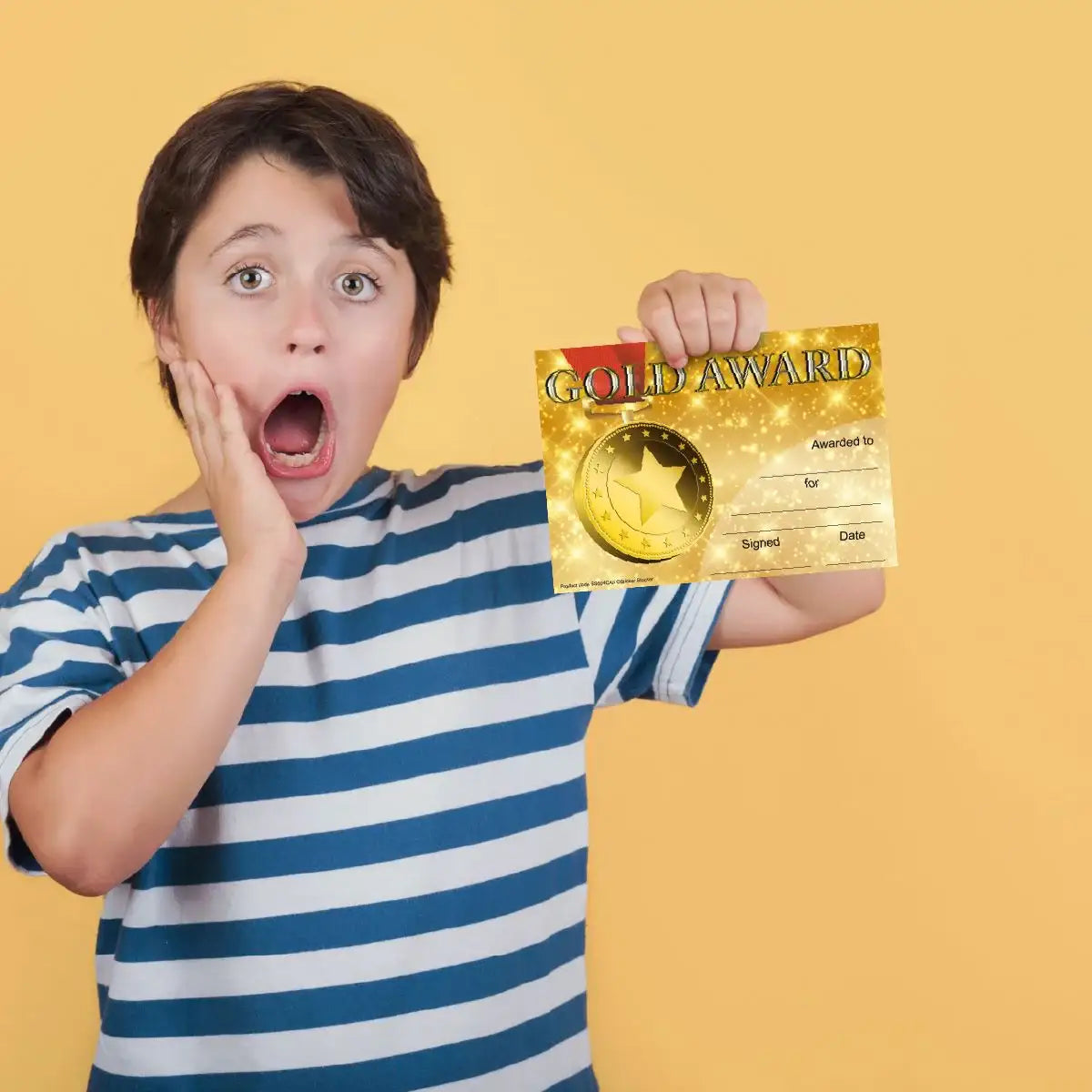 Excited child holding gold award certificate against yellow background, school reward concept