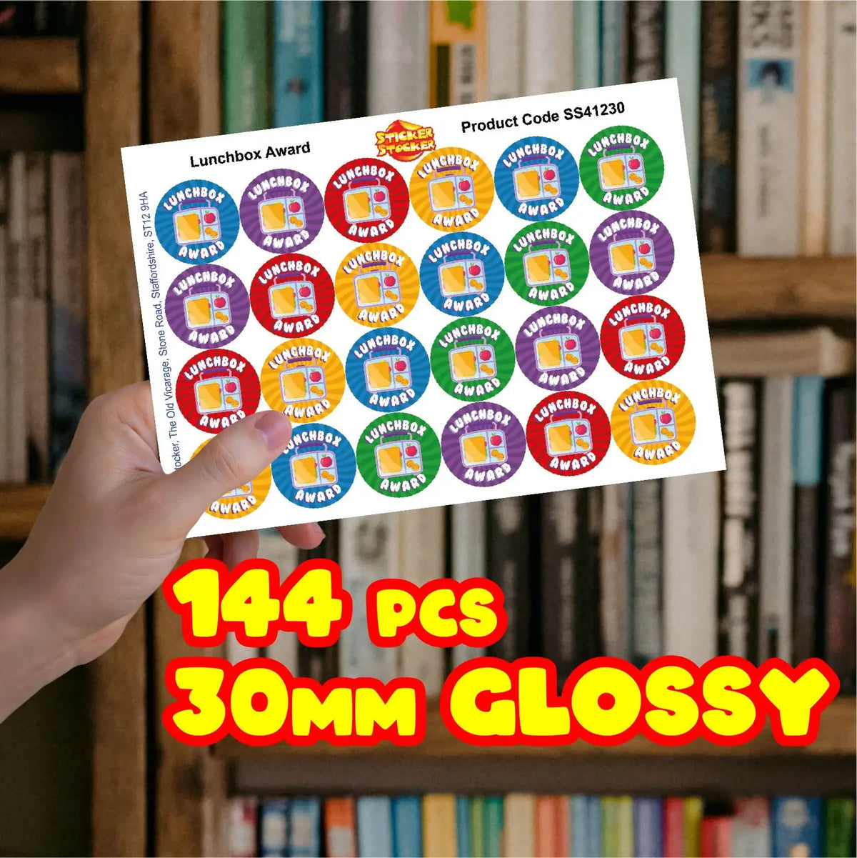 Hand holding sheet of colorful lunchbox award stickers, 144 pieces, 30mm glossy finish