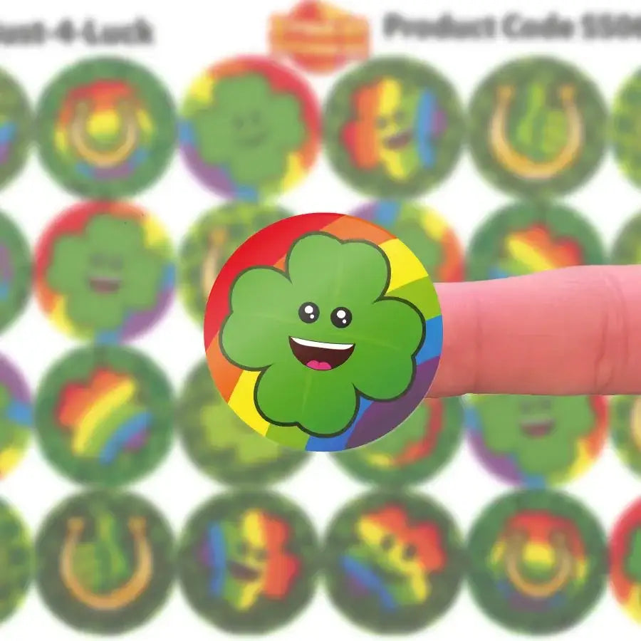 Smiling four-leaf clover reward sticker with rainbow border on fingertip, classroom stickers