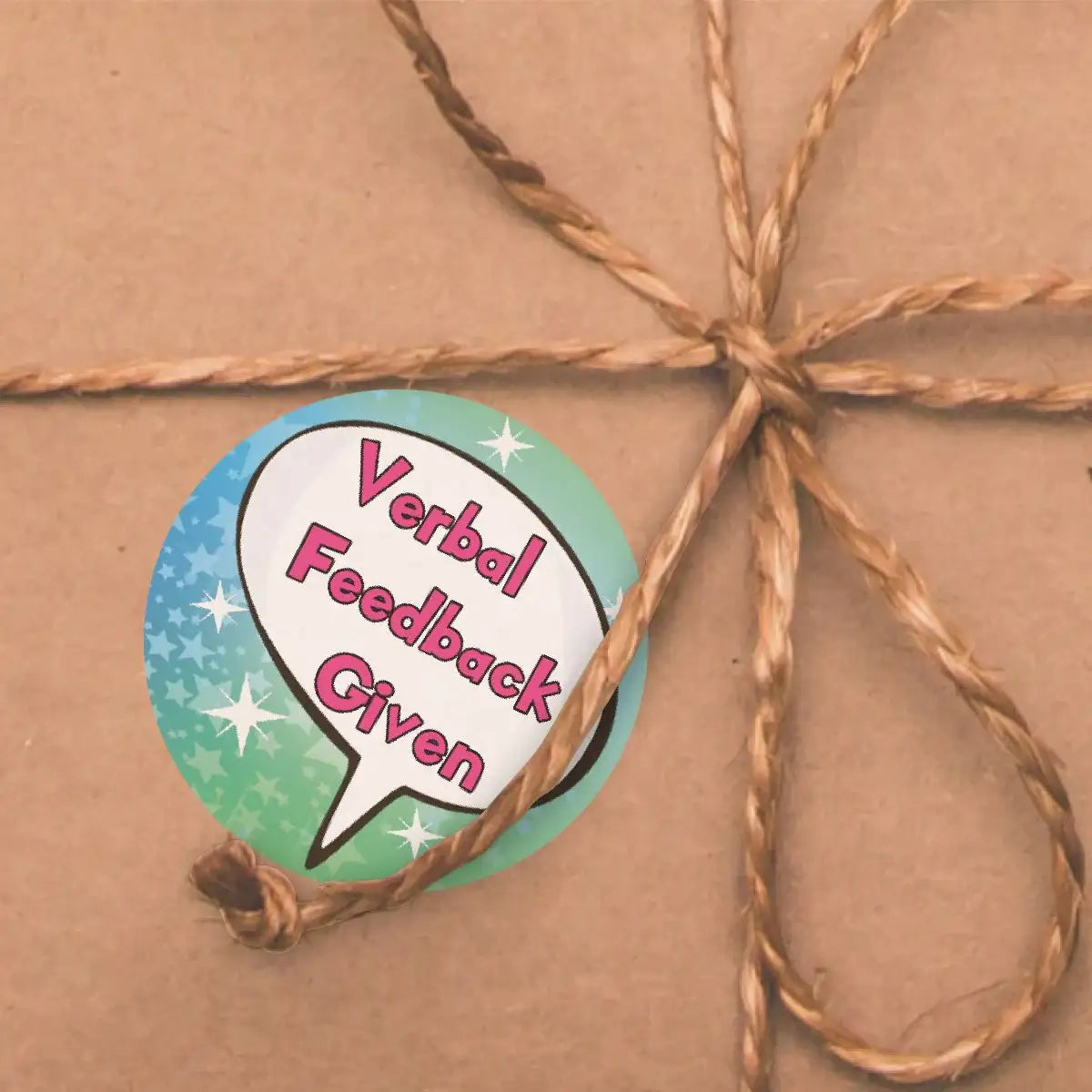 Verbal feedback given sticker with speech bubble on brown paper gift tied with twine.
