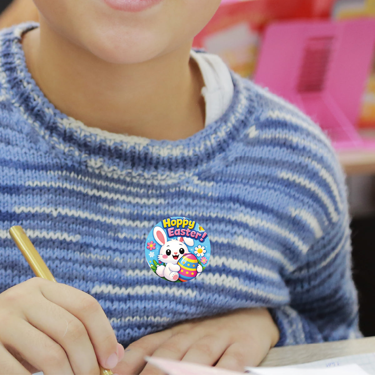 Child wearing Hoppy Easter bunny reward sticker on striped sweater in classroom